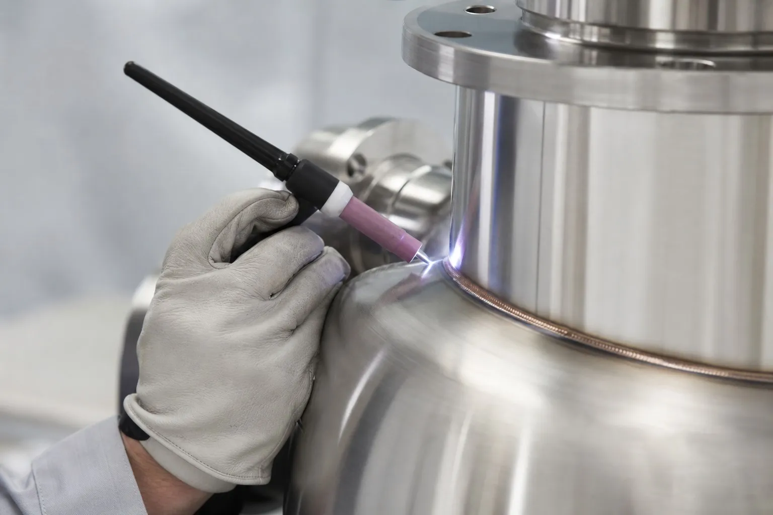 A TIG torch laying a bead along the seam of a polished stainless steel vessel